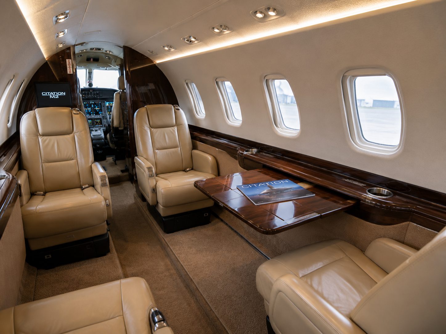 Cabina del Citation M2 con mesa de trabajo y butacas de cuero